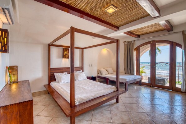 A four-poster bed in a room with a view of the beach. - Hotel Alcazar (San Juan del Sur)