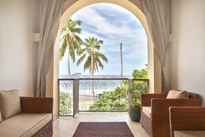 A balcony with wicker furniture, a view of the ocean, and palm trees. - Hotel Alcazar (San Juan del Sur)