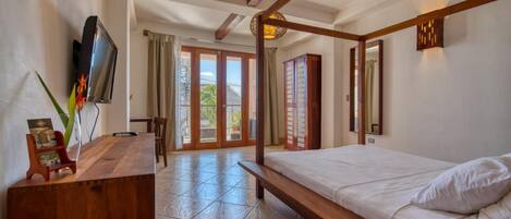 A bedroom with a wooden bed, a desk with a TV, and a view of the outdoors through a glass door.