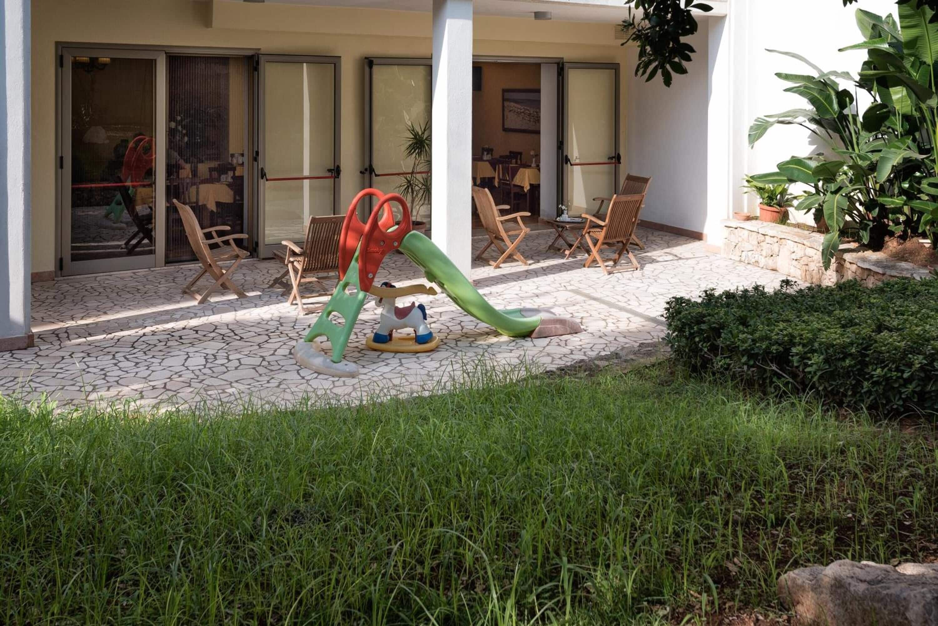 A patio area with outdoor furniture, a children's play structure, and potted plants.