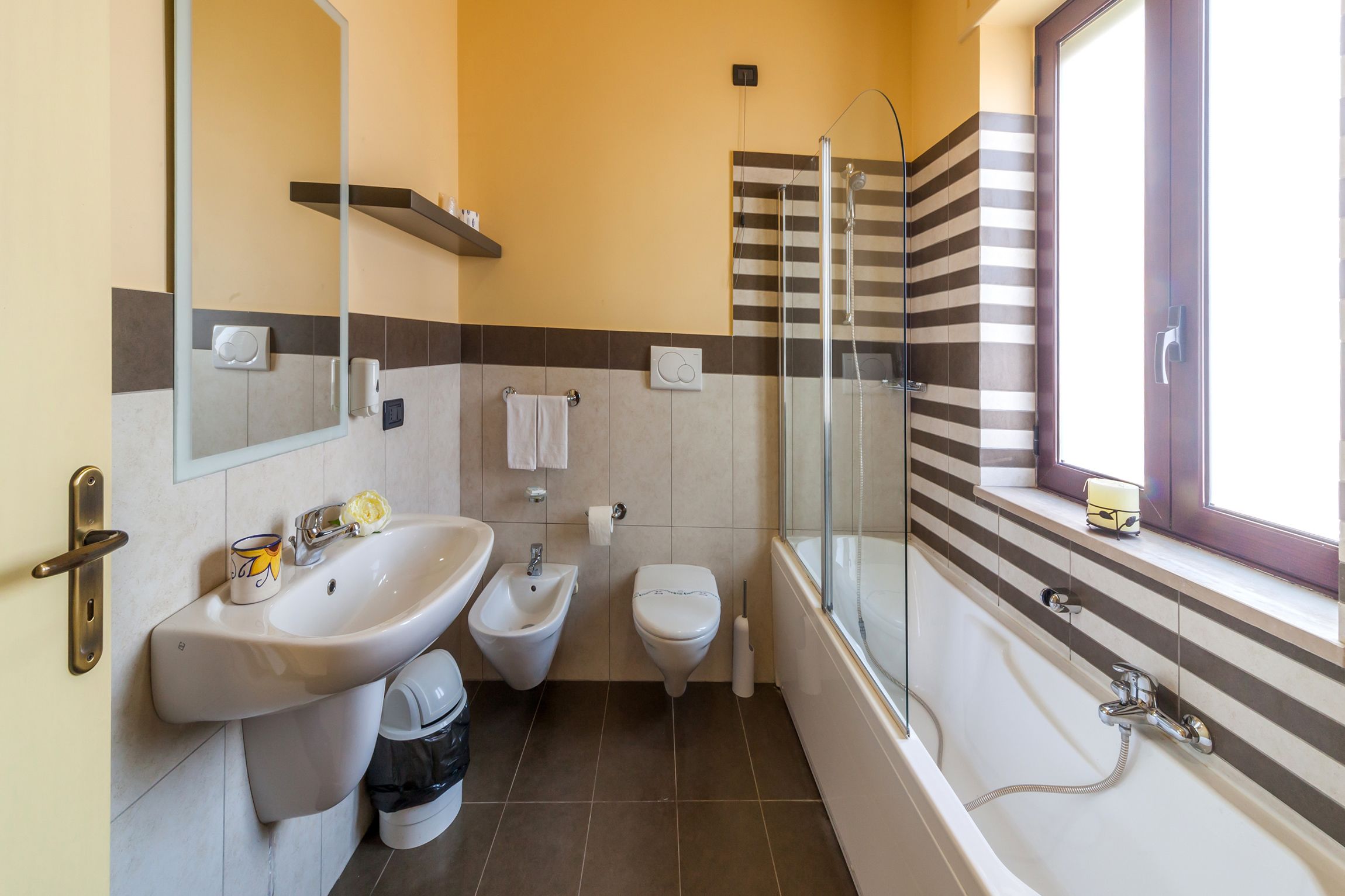 A bathroom with a sink, bidet, toilet, and a glass-enclosed shower.