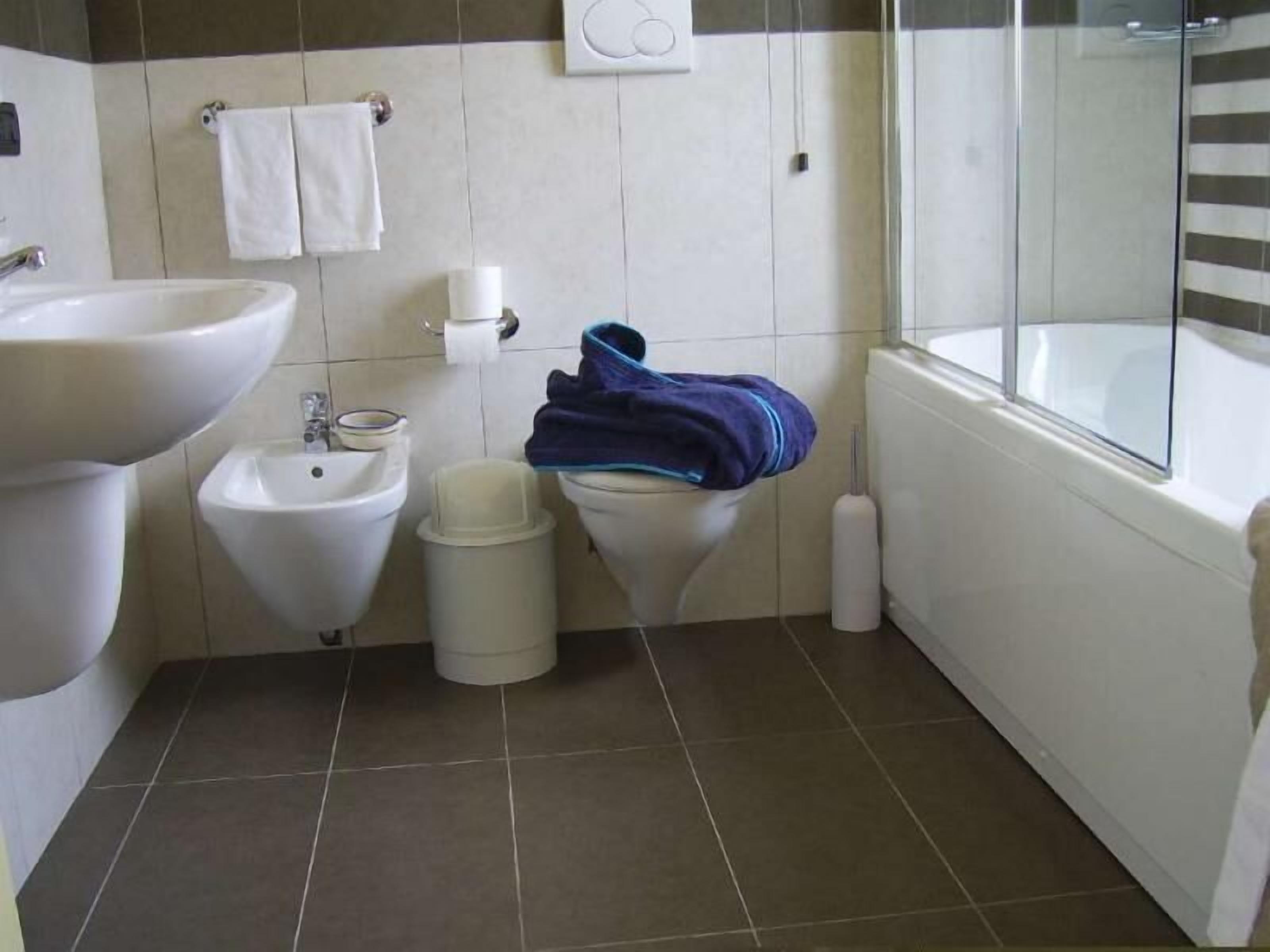 A bathroom with a sink, bidet, toilet, and bathtub.