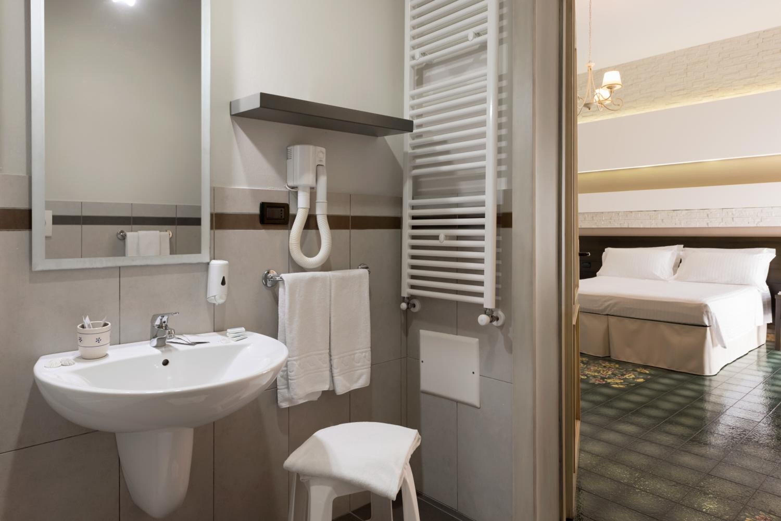 A modern bathroom with a sink, towel rack, and a visible heater.