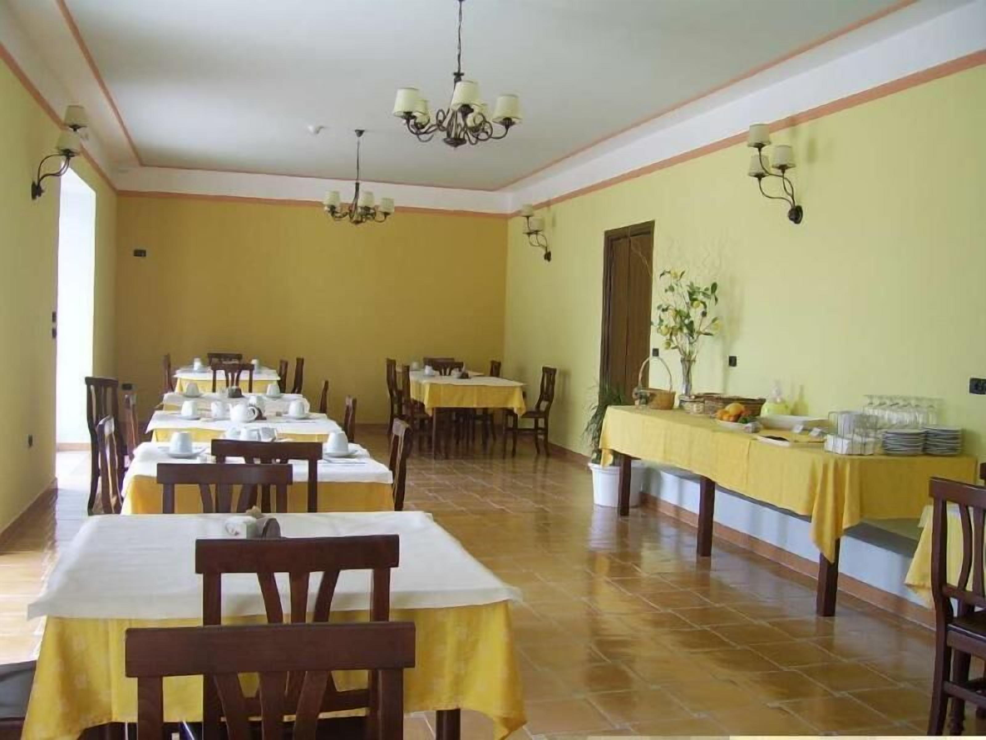 A dining area with multiple tables and chairs, yellow walls, and ceiling chandeliers.