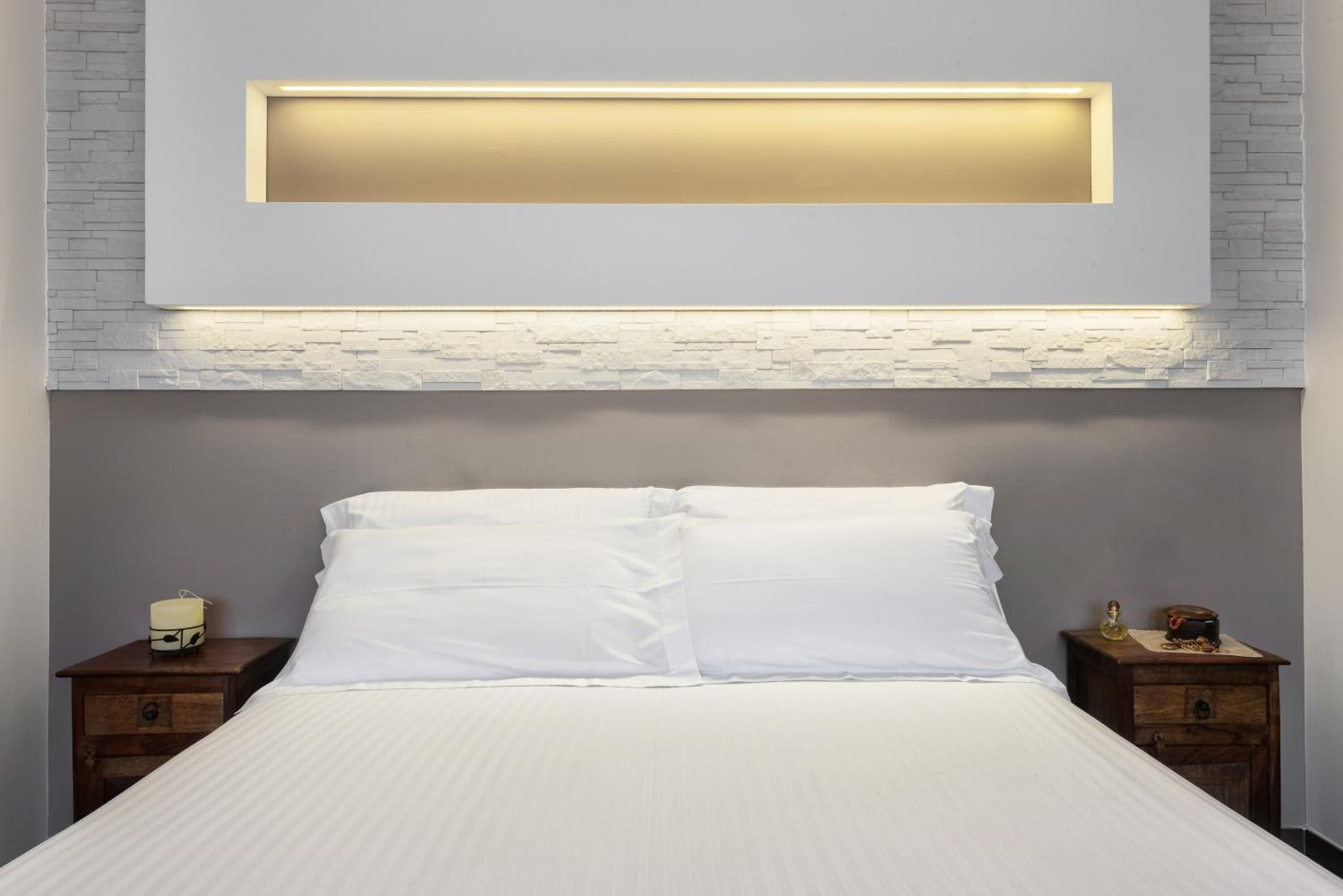 A modern bedroom with a bed, nightstands, and a wall-mounted light fixture.