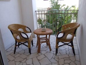 A balcony with two wicker chairs and a small round table, featuring a stone floor and a view of greenery. - La Chiocciola (Castrignano del Capo)