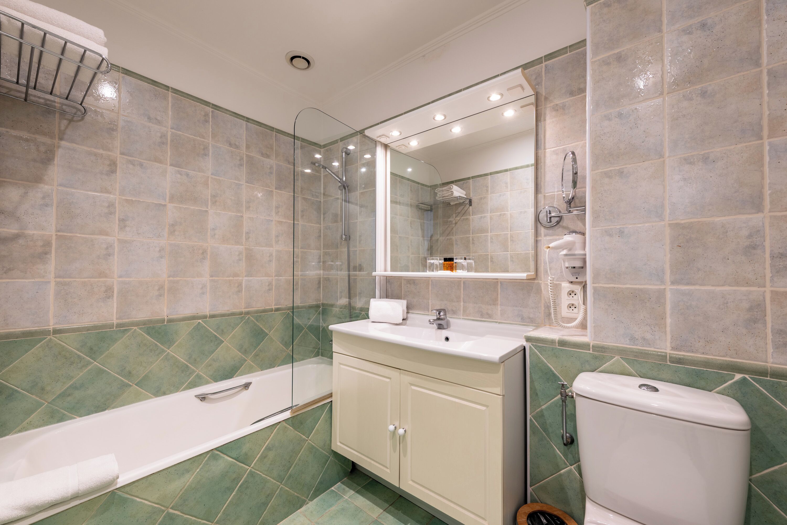 Et badeværelse med badekar, toilet, håndvask og brusebad.