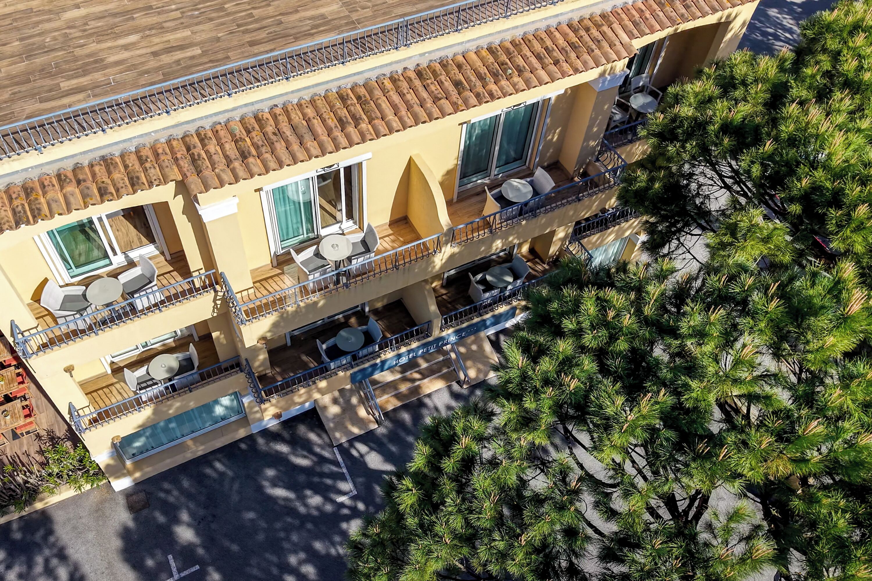 A multi-story hotel with balconies, outdoor seating, and a tiled roof.