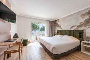 Una habitación de hotel con una cama, un escritorio, una silla y un televisor.