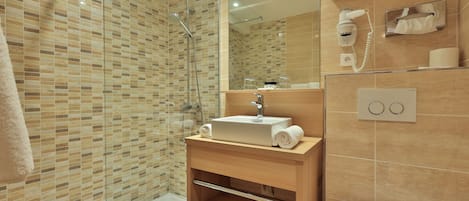 A modern bathroom with a glass shower enclosure, a sink with a towel, and a toilet.