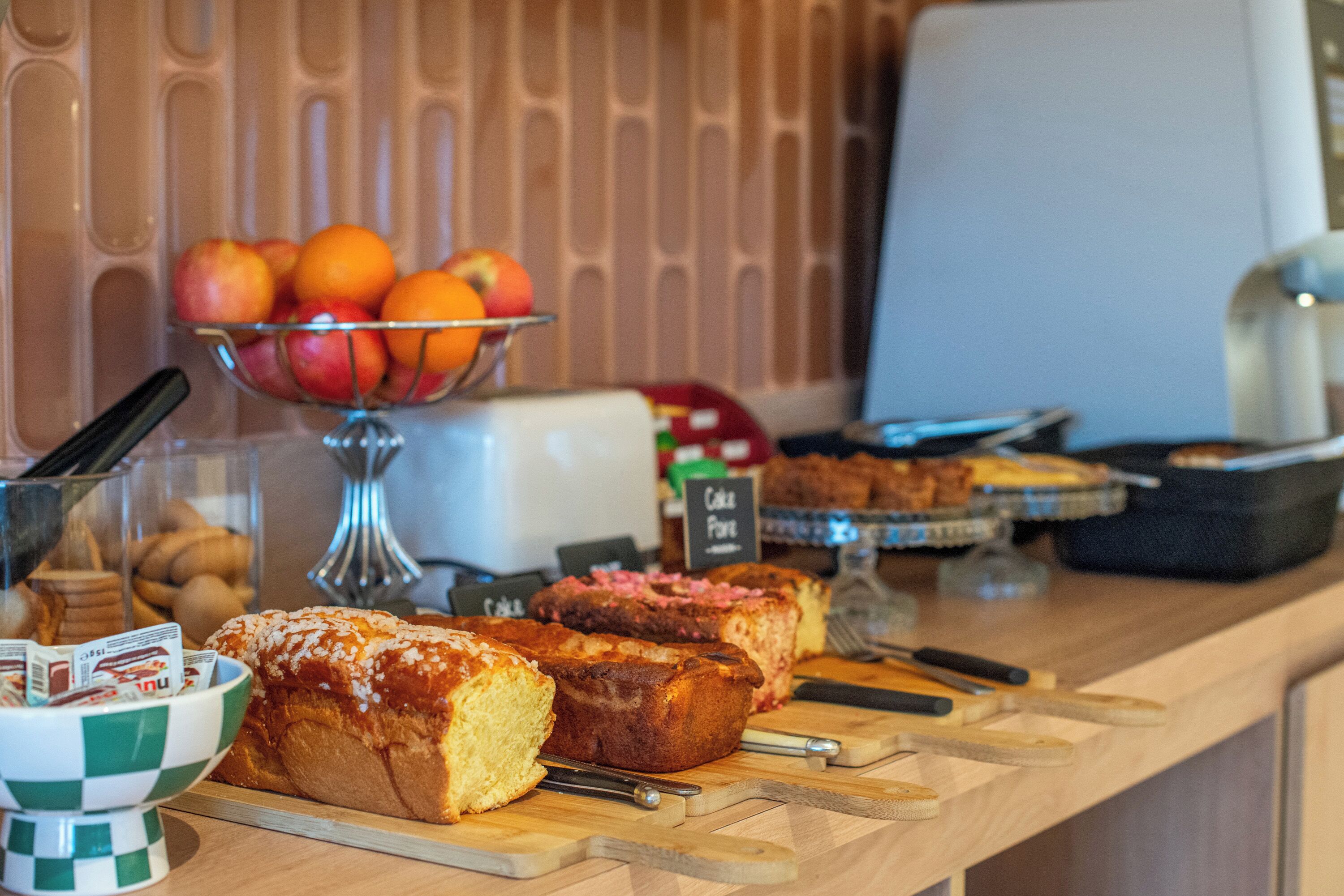 Un bufé de desayuno con diversos productos de panadería y frutas.