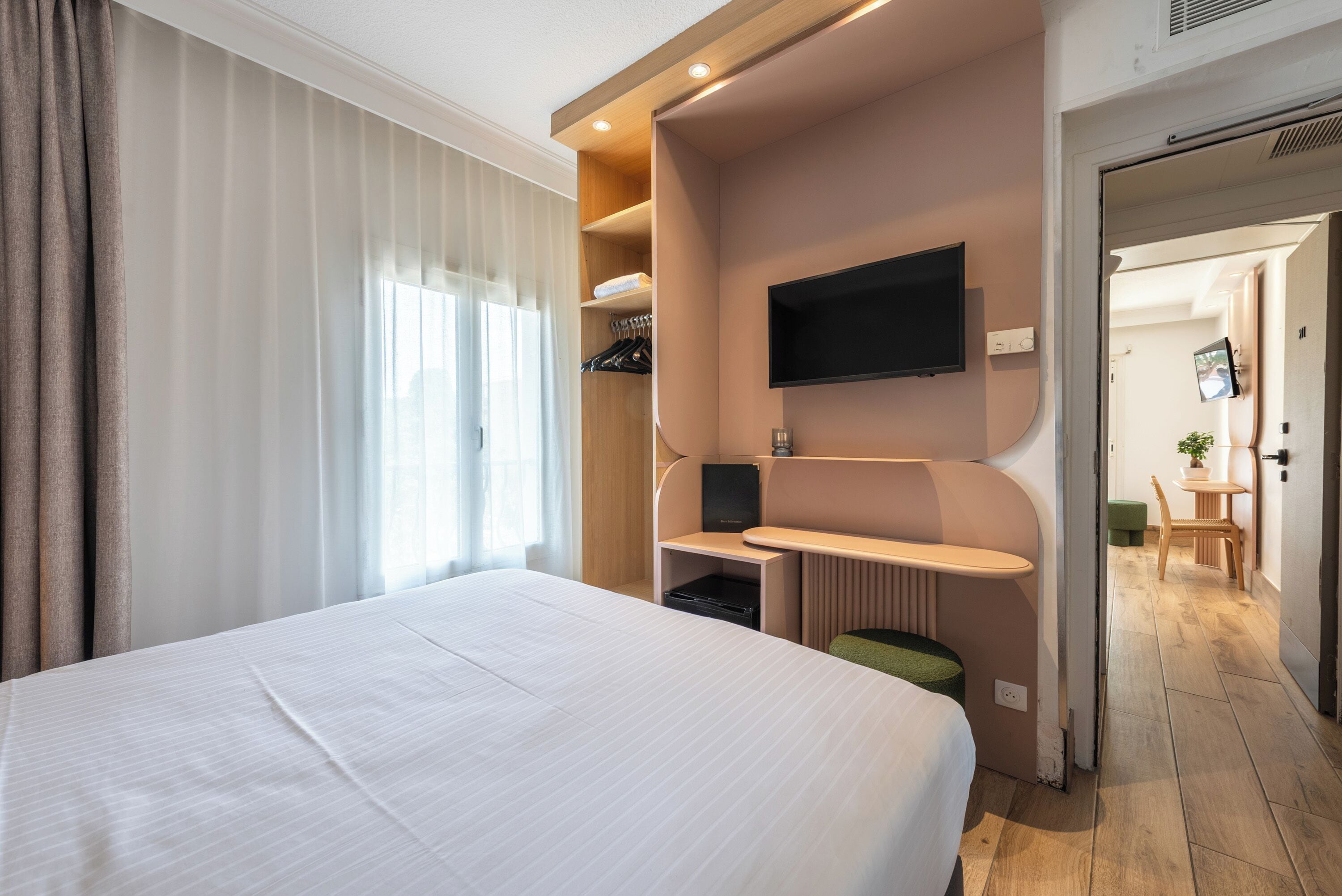 Ein Hotelzimmer mit einem großen Bett, einem Schreibtisch, einem Flachbildfernseher, einer Sitzecke und Blick auf den Flur.