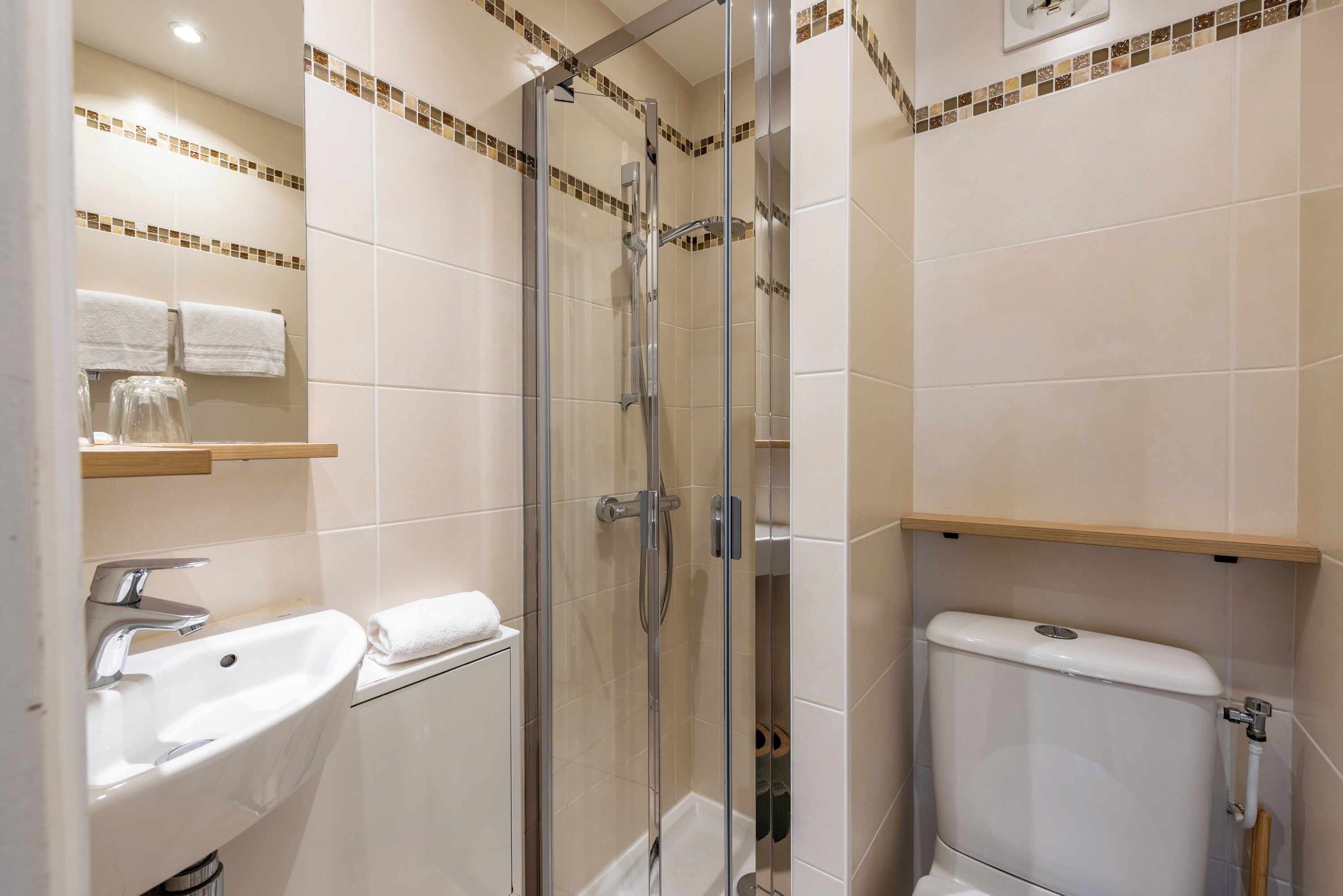 A bathroom with a glass-enclosed shower, a sink, and a toilet.