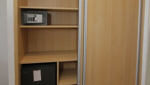 A room with a sliding wooden wardrobe, a black mini-fridge, and a shelf unit. - Hotel Le Petit Prince (Sainte-Maxime)