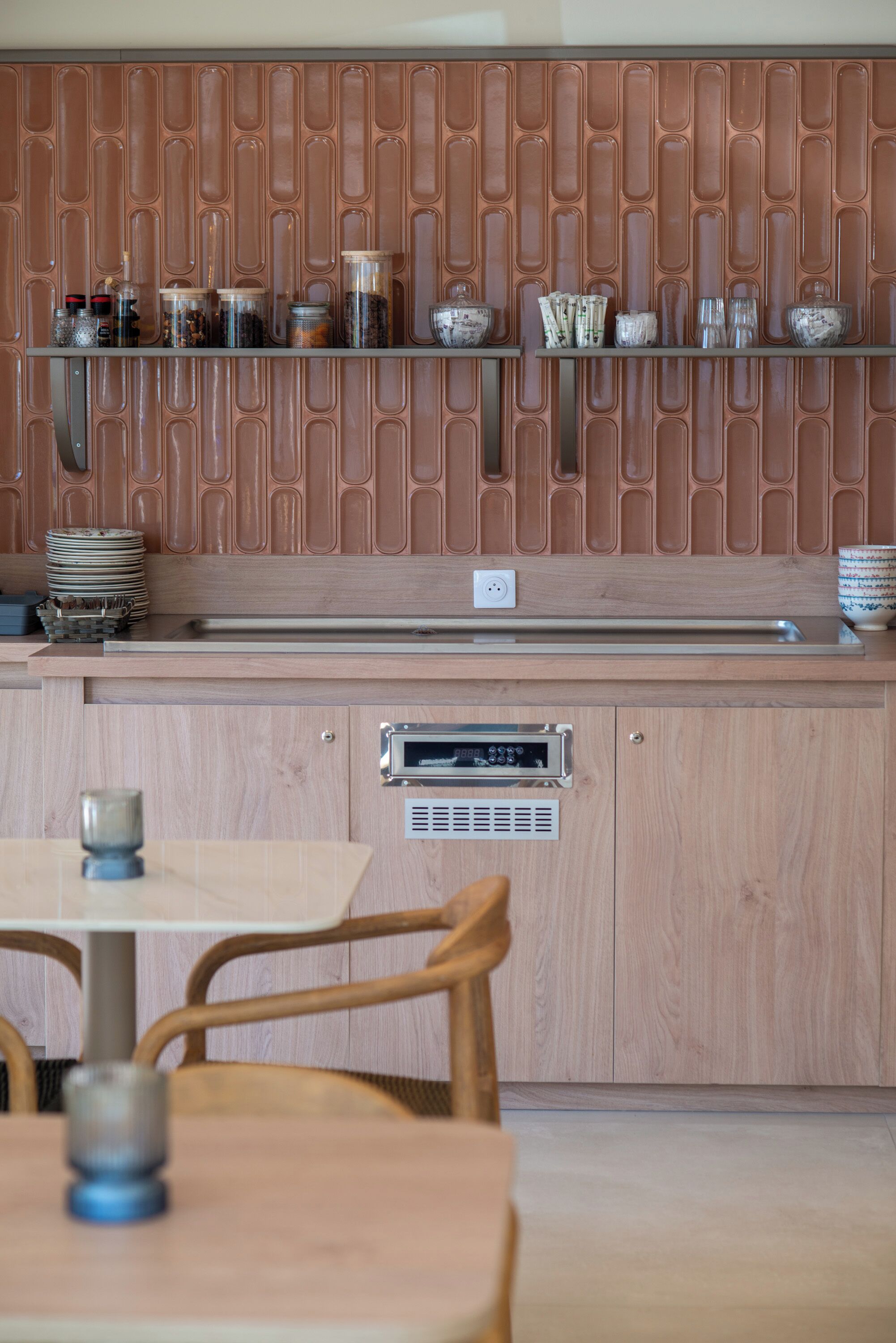 Una cocina con un panel de madera en la pared salpicadero, electrodomésticos de acero inoxidable y un comedor con mesa y sillas.