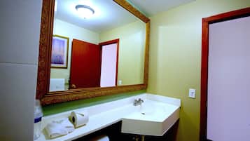 Un baño con lavamanos blanco, un espejo de marco decorativo, una toalla y un inodoro.