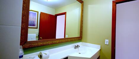 A bathroom with a white sink, a mirror with an ornate frame, a towel, and a toilet.