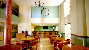 Un restaurante con varias mesas y sillas de madera, un gran reloj de pared y un televisor montado.