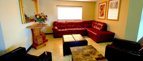 A living room with a red leather sofa, a wooden coffee table, and a large mirror on the wall.