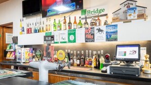 A bar area with a variety of liquor bottles, a television screen, and a POS system. - The Bridge (Smithton)