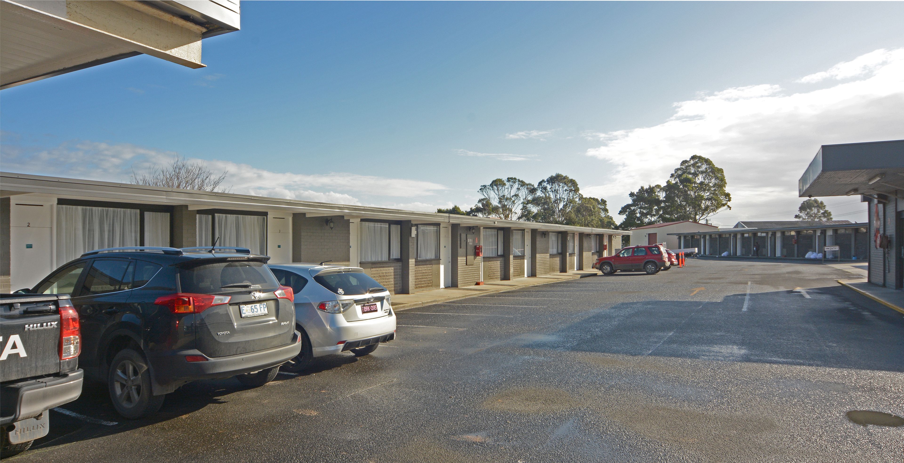A parking lot with several cars, a building with a flat roof, and a clear sky.