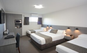 Habitación de hotel con dos camas individuales, un escritorio con microondas, televisión y una silla.