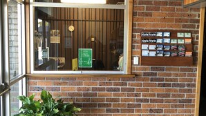 A brick wall with a window, a clock, and a sign about social distancing. - The Bridge (Smithton)