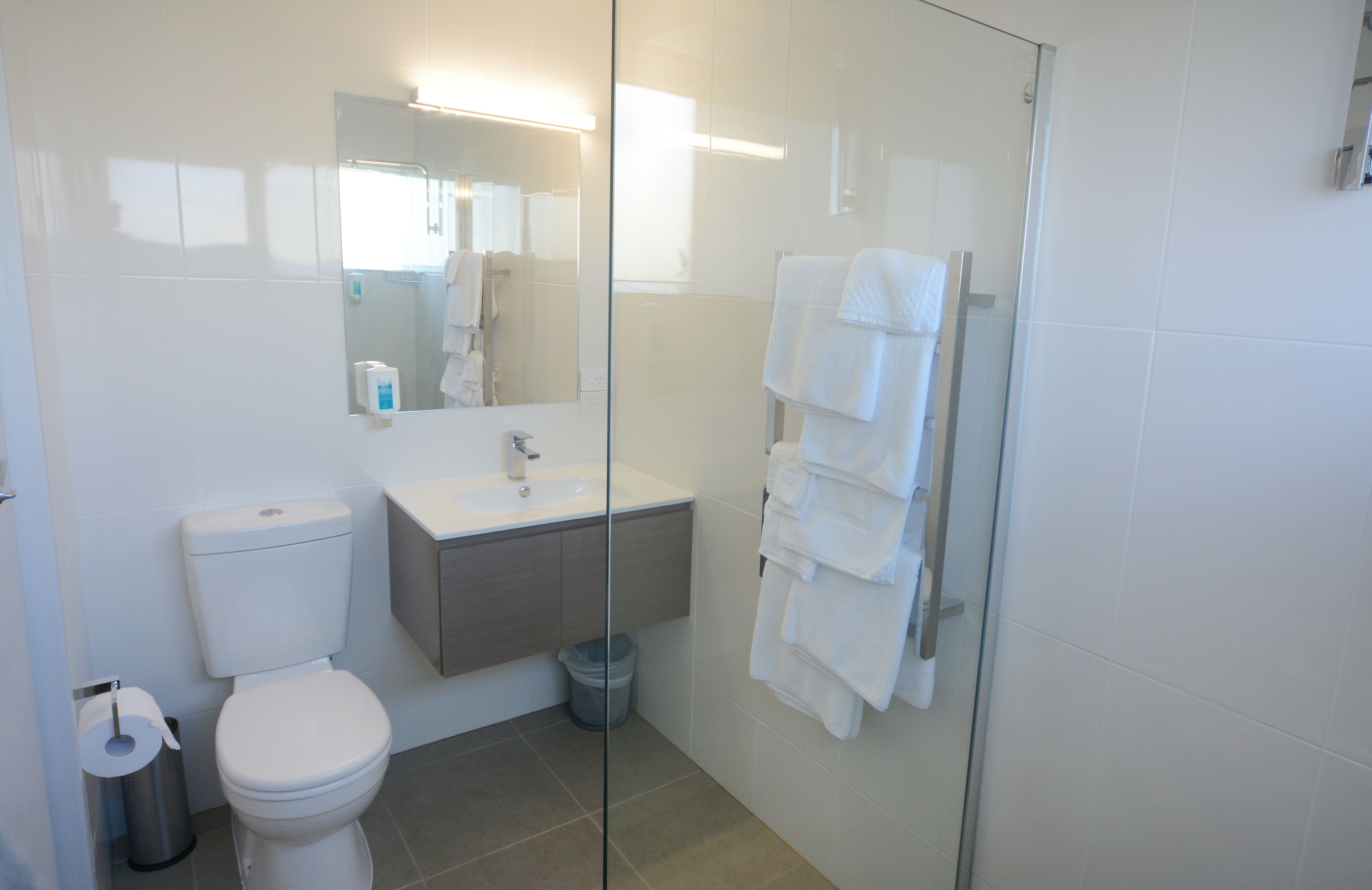 Ein modernes Badezimmer mit Toilette, Waschbecken und einer Duschkabine aus Glas.