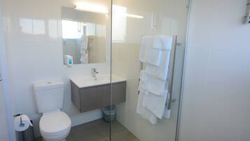 Ein modernes Badezimmer mit Toilette, Waschbecken und einer Duschkabine aus Glas.