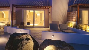 Zona d'estar exterior moderna amb piscina, gandules i entrada ben il·luminada.