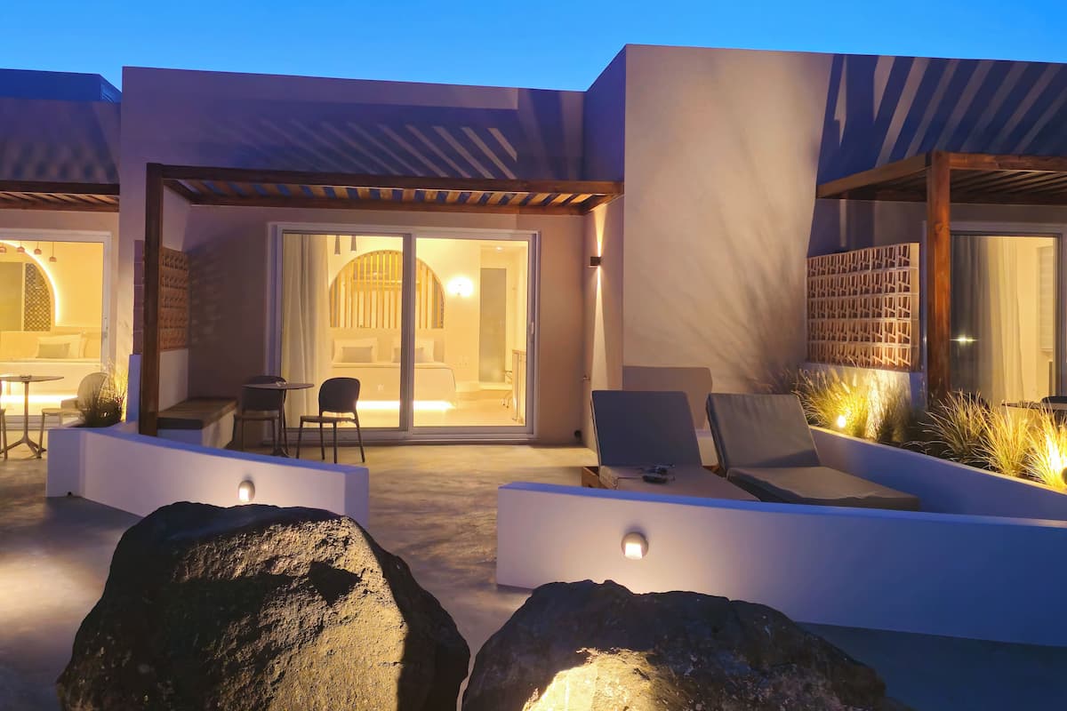 A modern outdoor seating area with a pool, lounge chairs, and a well-lit entrance.