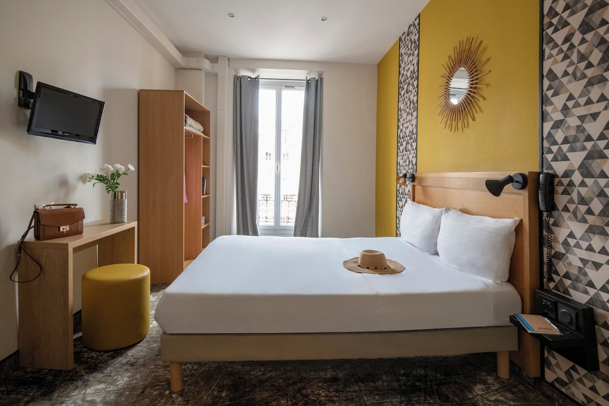 Una habitación de hotel con cama, escritorio, silla, televisor y baño.