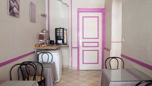 Una habitación compacta con kitchenette, un comedor con sillas y una puerta de marco rosa.