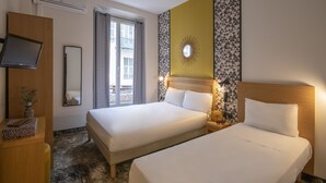 Habitación de hotel con dos camas, televisión, espejo y ventana con cortinas.