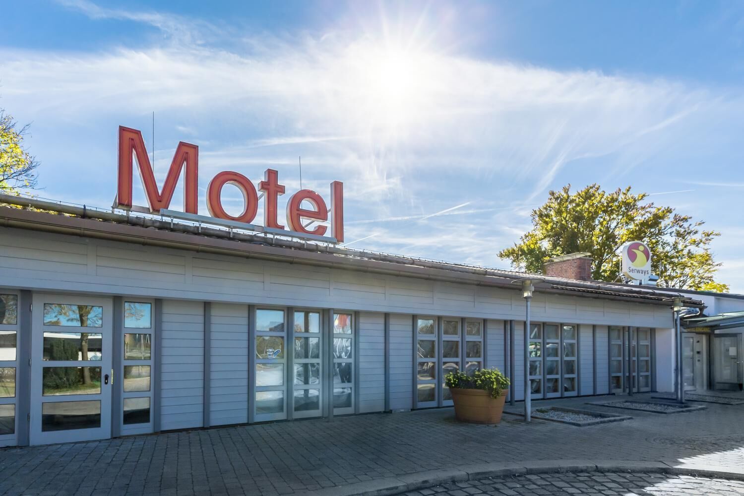 A motel with a prominent 'Motel' sign, large windows, and a parking area.