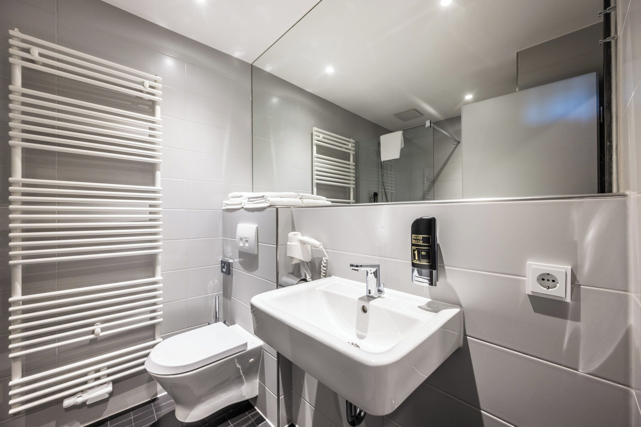 A modern bathroom with a white sink, toilet, and towel rack.