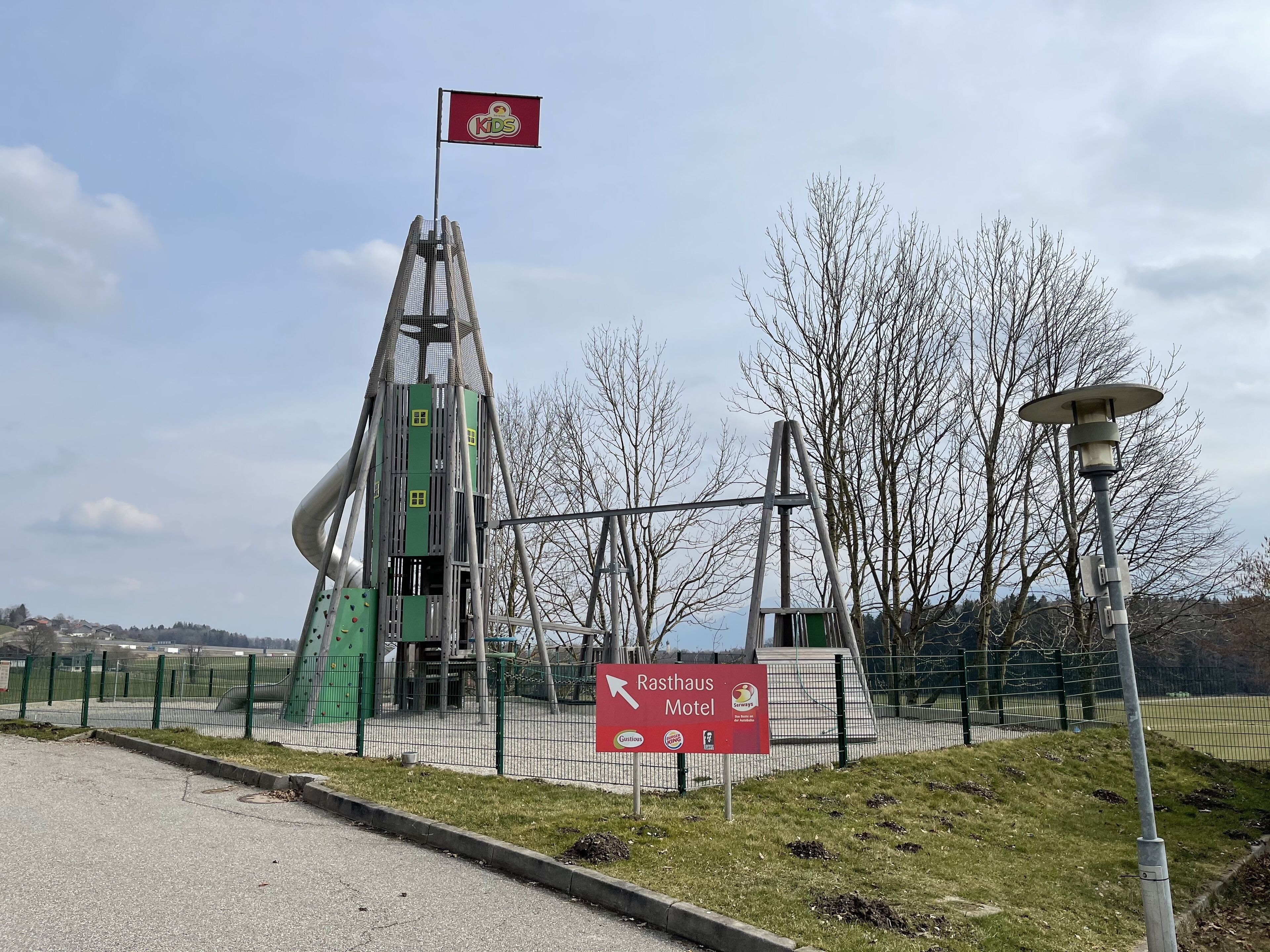 Una estructura de juegos con una bandera, un cartel que dice Rasthaus Motel y un farol.