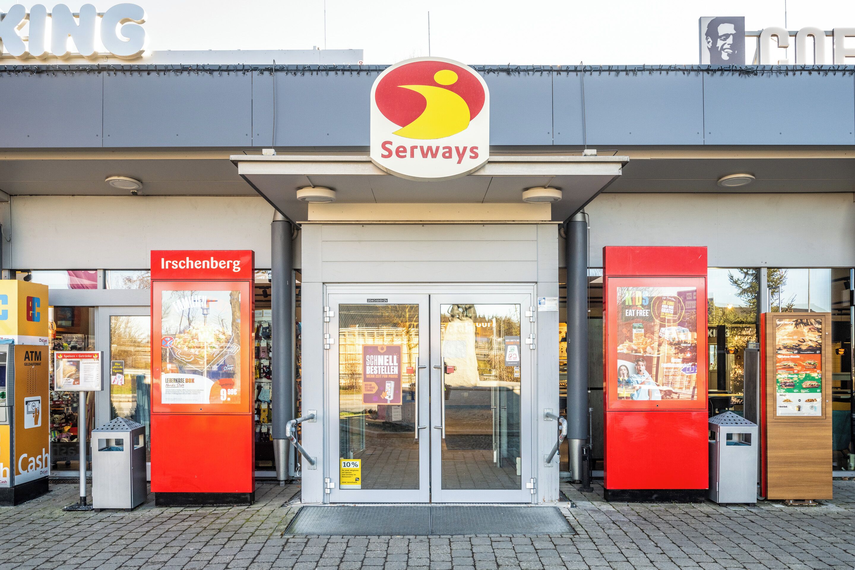 A Serways store with a glass door entrance, red signage, and a visible ATM on the left.