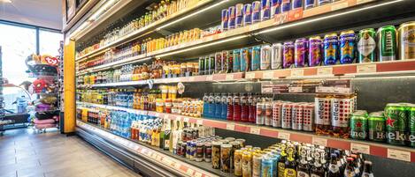 Una sección refrigerada en una tienda con diversas bebidas, incluyendo latas y botellas, sobre estantes.
