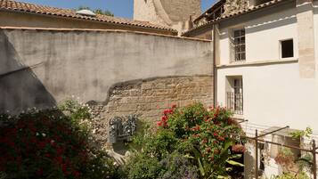 A courtyard with a tower, potted plants, and a building with a tiled roof.