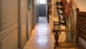 Un couloir avec un banc en bois, un porte-bouteilles fixé au mur et une porte au fond.