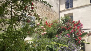 Une cour agrémentée de diverses plantes à fleurs et d’une statue.