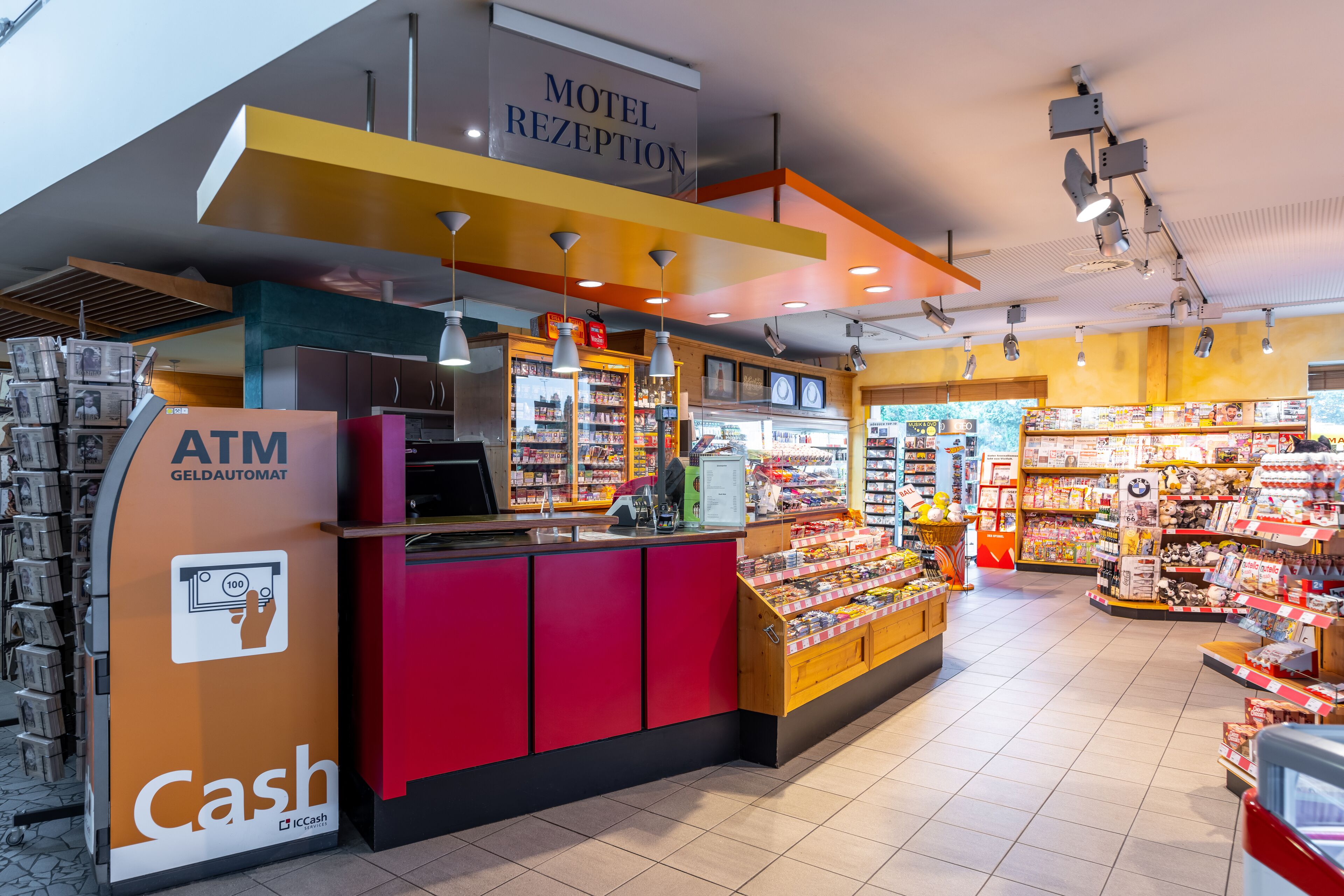 Zona de recepción de un hotel con cajero automático, mostrador de efectivo y diversas comodidades, como un minibar y una tienda de regalos.