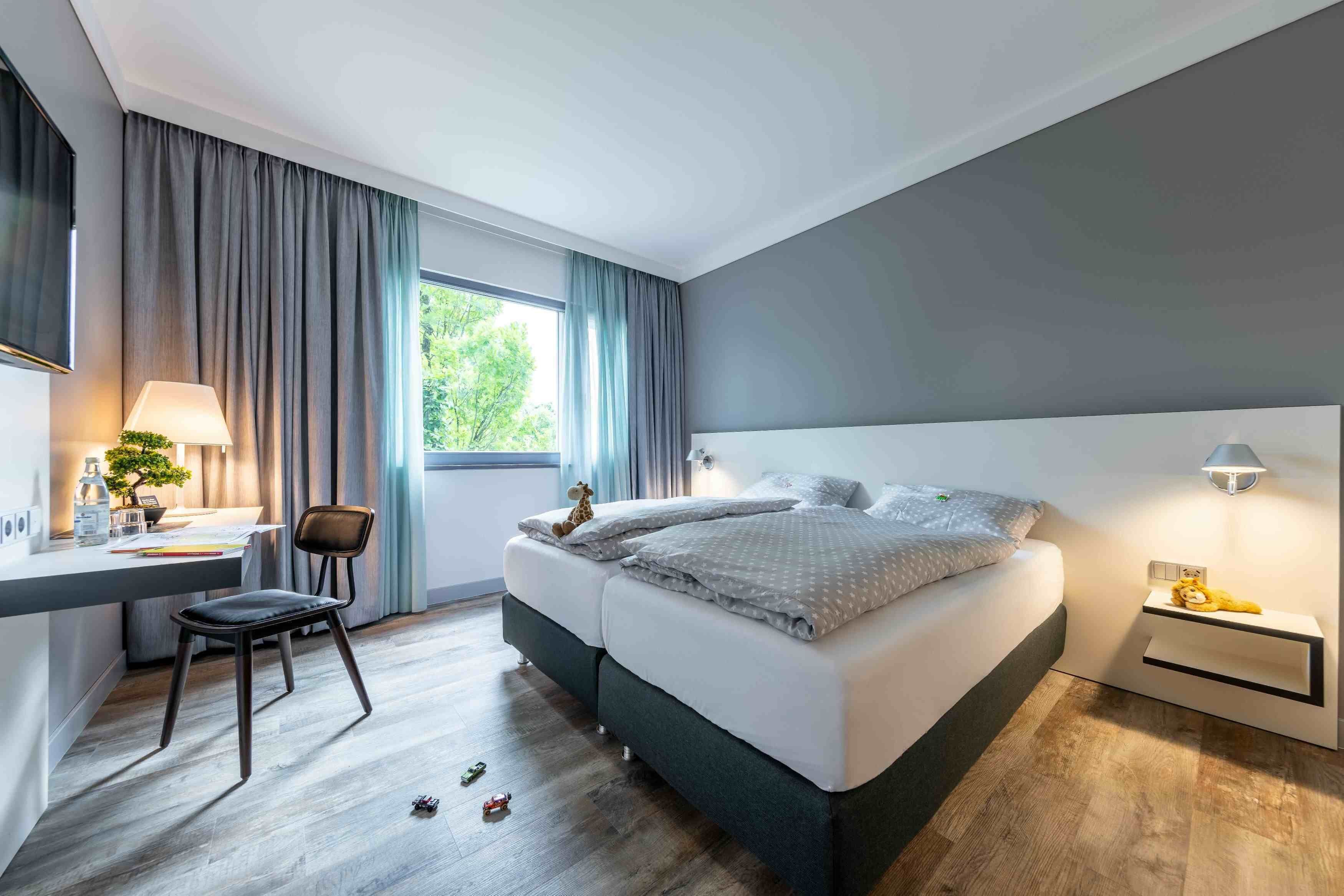 Een moderne slaapkamer met een bed, nachtkastje, lamp en bureau met stoel.