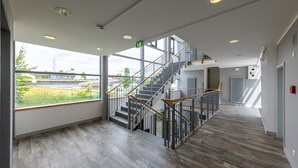 Un interior moderno con una escalera, ventanas amplias y vistas a zonas verdes.