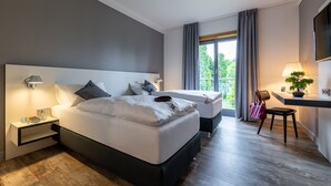 Un dormitorio moderno con una cama grande, mesitas de noche, un escritorio con silla y un televisor montado en la pared.