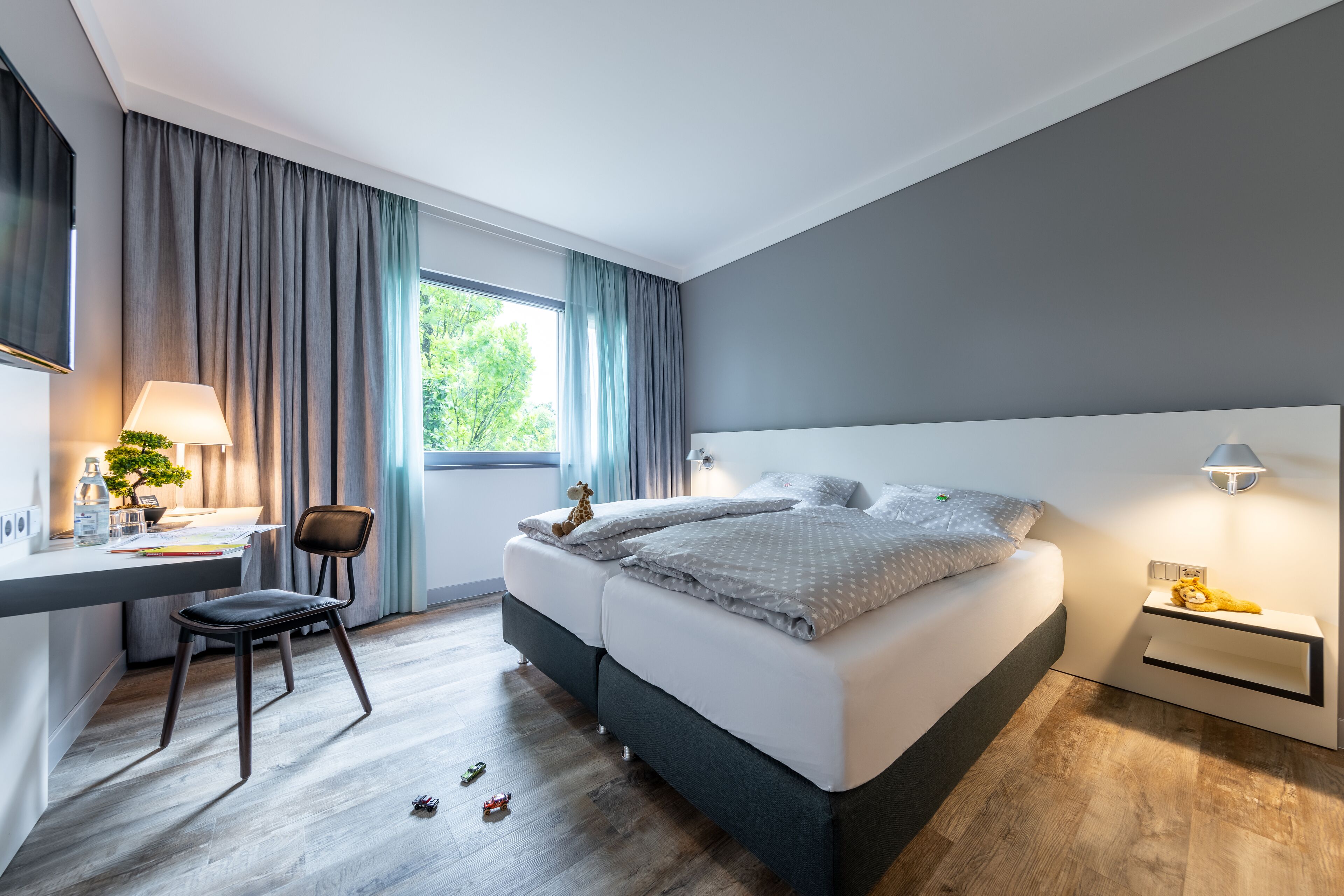 Une chambre à coucher moderne avec un grand lit, un bureau avec une chaise et une fenêtre avec des rideaux.