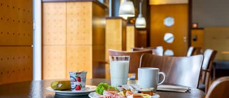 Une table de petit-déjeuner avec des assiettes remplies de nourriture, un verre de lait et une tasse.