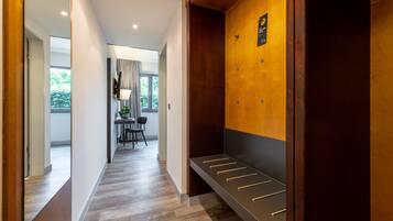 A modern hotel hallway with a wooden bench, a coat rack, and a television mounted on the wall.