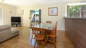 Un salon comprenant un téléviseur, un canapé, une table à manger, des chaises et un ventilateur de plafond.